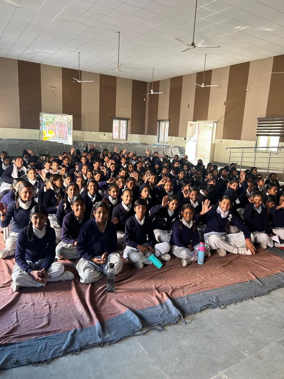 Schoolgirls smiling and waving at an awareness session